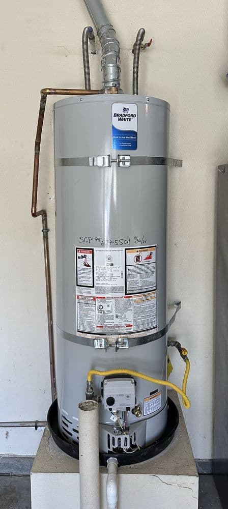 Bradford White water heater with 'SCP 951-679-5501' and the install date hand-written on the tank by Sun City Plumbing