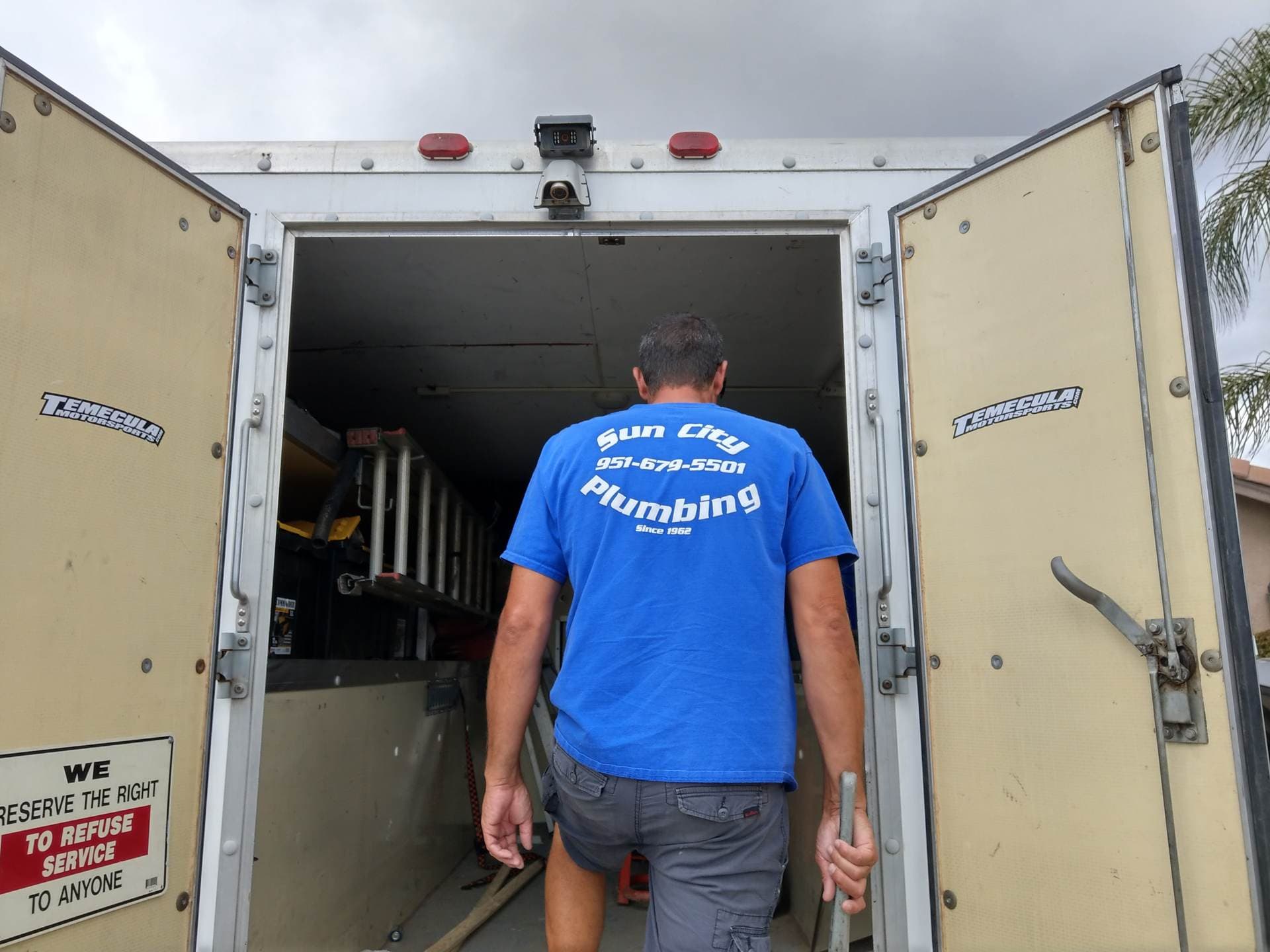 Chris of Sun City Plumbing in his blue uniform shirt, loading his box truck in Menifee